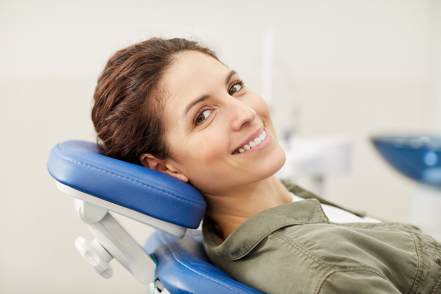 Portrait of smiling young woman lying in dental chair and looking at camera, copy space