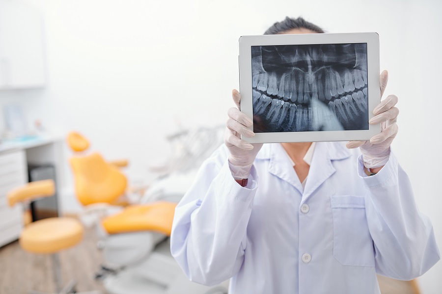 Dentist holding digital tablet with teeth x-ray on screen and looking for any inflammation